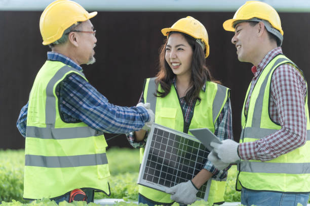 istock Engineers construction inspecting a solar panel device for greenhouse for cultivation of vegetable food. Technician workers talking to choose high efficiency photovoltaic panel for renewable energy. 1353255562