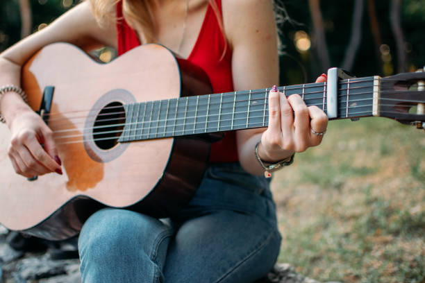 istock Creative hobbies, guitar lessons, playing musical instruments. Acoustic guitars for beginners. Young blonde woman with Acoustic guitar outdoor 1353257854