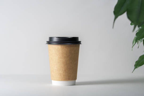 istock Mockup of a paper cup illuminated by soft light on a gray background. 1353261011