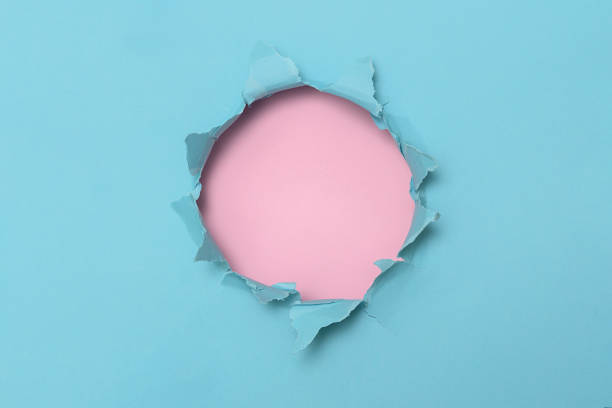 istock Hole in the blue paper with a pink blank background for text. 1353261081