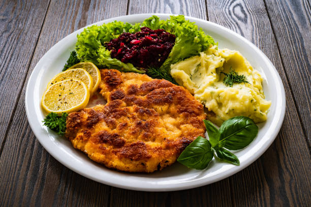 жареная свиная отбивная с лимоном и свежими овощами на черном столе - cutlet pork steak schnitzel стоковые фото и изображения