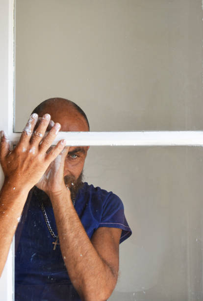 istock A sad and worried man stared out the window, his hands smeared with paint 1353265647