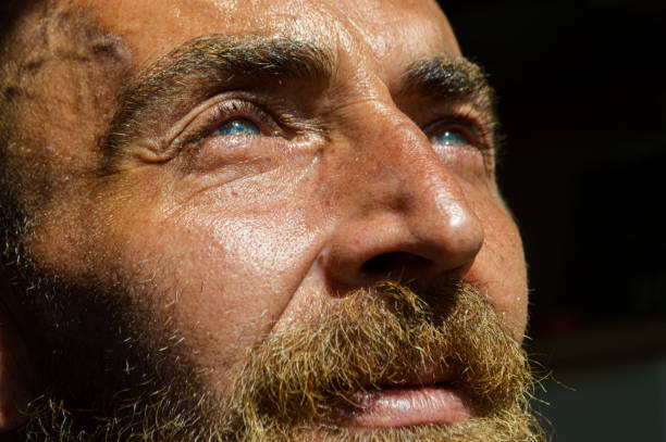 This close-up shot of a grim, frowning, furious businessman with jaw clenched glaring at something is distorted by the use of a fisheye lens.