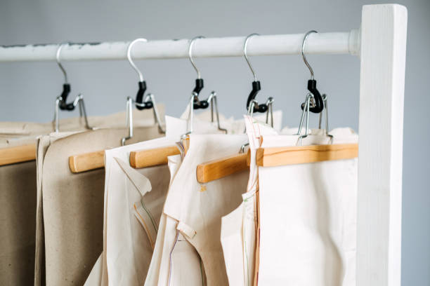 istock Many paper sewing patterns for different clothes hanging on the rack in sewing factory background. Clothing pattern, manufacture on sewing factory. Tailoring, small business 1353265838
