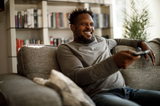 istock Smiling man watching tv in living room 1353265979