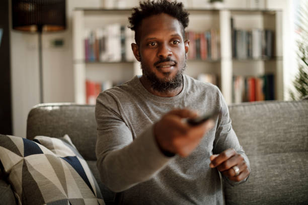 istock Excited man holding remote control and changing channel at home 1353266093