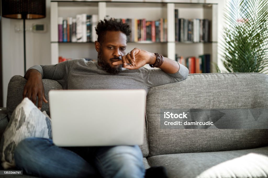 Young man watching movie on laptop at home Confusion Stock Photo