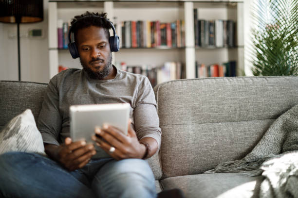 istock Young man with wireless headphones using digital tablet at home 1353266791