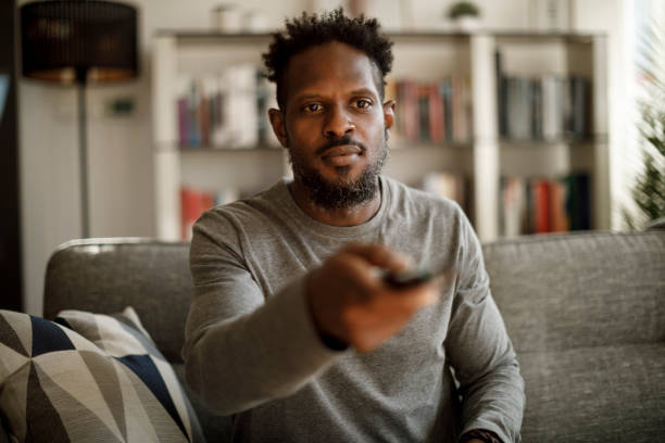 istock Man holding remote control and changing channel at home 1353266914