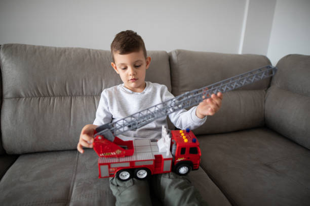 istock Young boy playing with fire truck toy 1353269631