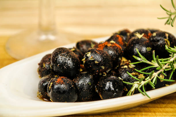 schwarze oliven gewürzt mit paprika, olivenöl und oregano - pepper spice dried plant image stock-fotos und bilder