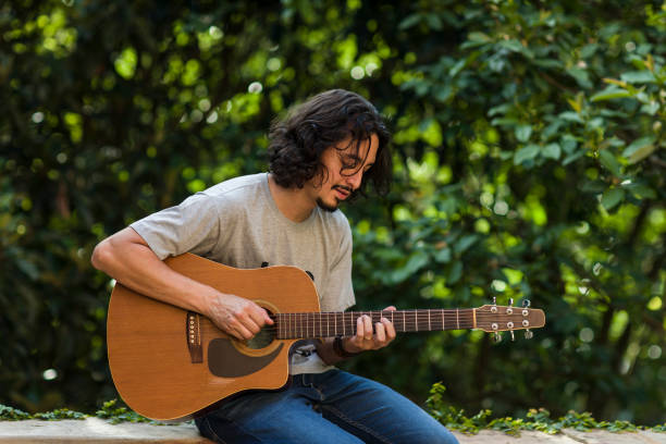 istock Man playing guitar on parapet amid nature 1353274462