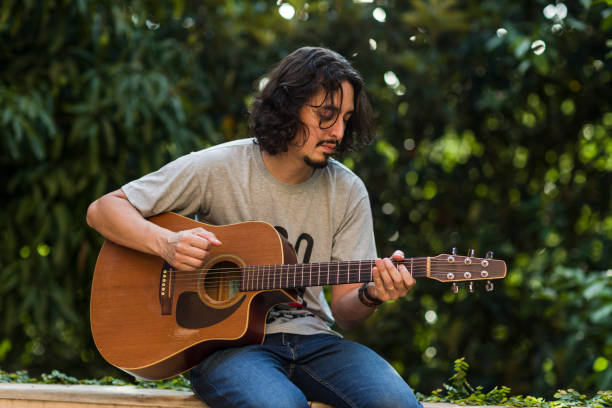 istock Man playing guitar on parapet amid nature 1353274495