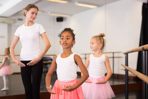 istock Dance teacher helping her little girls students 1353278818
