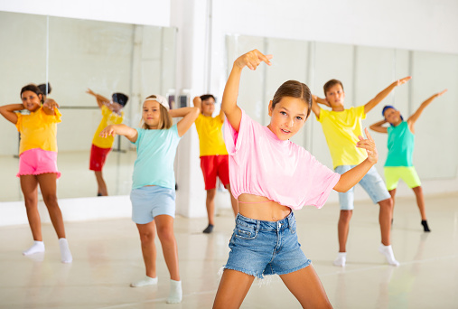 Portrait of modern tween girl krump dancer in choreographic studio with dancing children in background