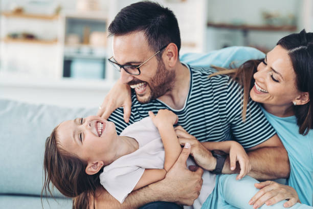 famiglia felice con una ragazza che si diverte a casa - tickling foto e immagini stock