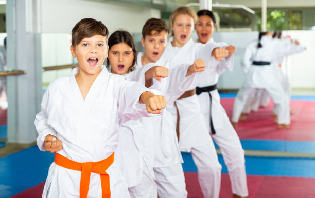 Team of motivated teenagers are engaged in karate in gym Team of motivated teenagers are engaged in karate in the gym karate stock pictures, royalty-free photos & images