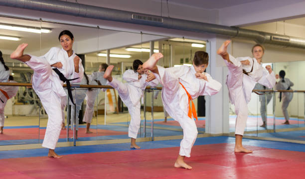 Kids and karate trainer training kicks in gym Kids and karate trainer demonstrating kicks in gym during group training. taekwondo photos stock pictures, royalty-free photos & images