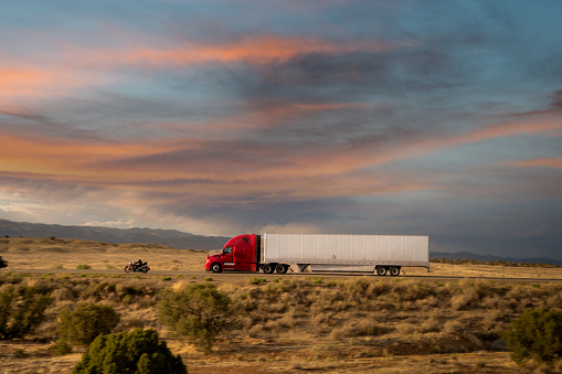 Red and white semi-truck driving in Utah mountain range