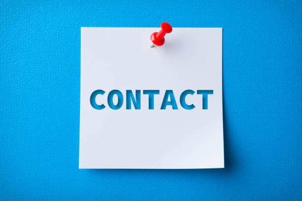 White Sticky Note With Contact Us And Red Push Pin On Blue Background
