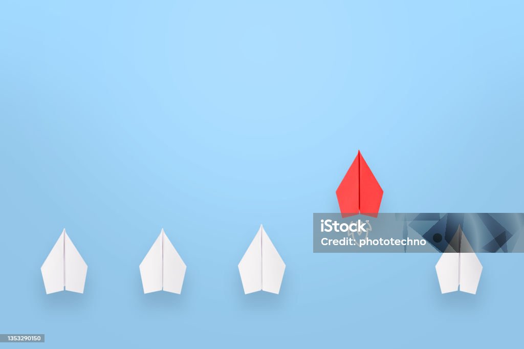 Change concepts with red paper airplane leading among white Group of paper plane in one direction and with one individual pointing in the different way, can be used leadership/individuality concepts. New idea, change, trend, courage, creative solution, innovation and unique way concept. Leadership Stock Photo
