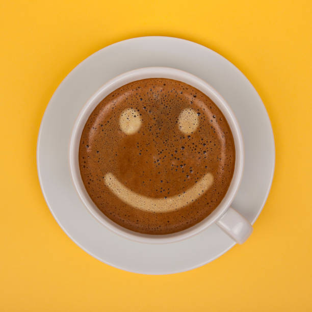 Coffee cup with smiley face on yellow background stock photo