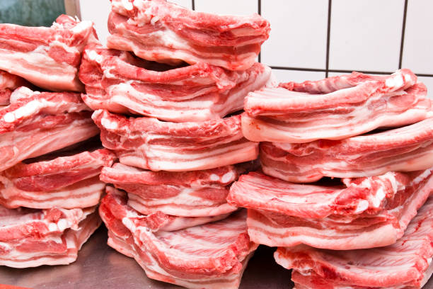 Stack of freshly pork bellies with spareribs on stainless steel table in butcher's shop.