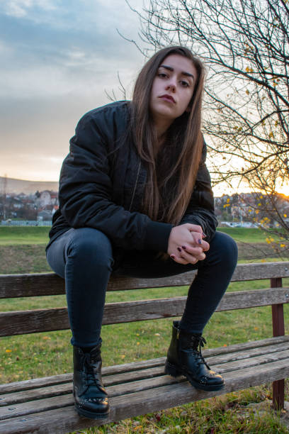 istock An urban dressed girl is sitting on a bench 1353290375