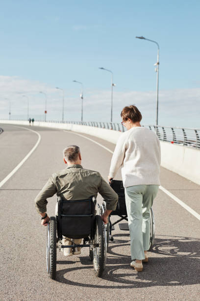 istock Couple with Man in Wheelchair Back View 1353290881