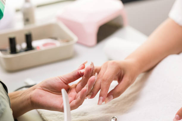 Brasilian latin mid woman manicure profesional file nailfiberflass nails to a client autumn evoque stock photo