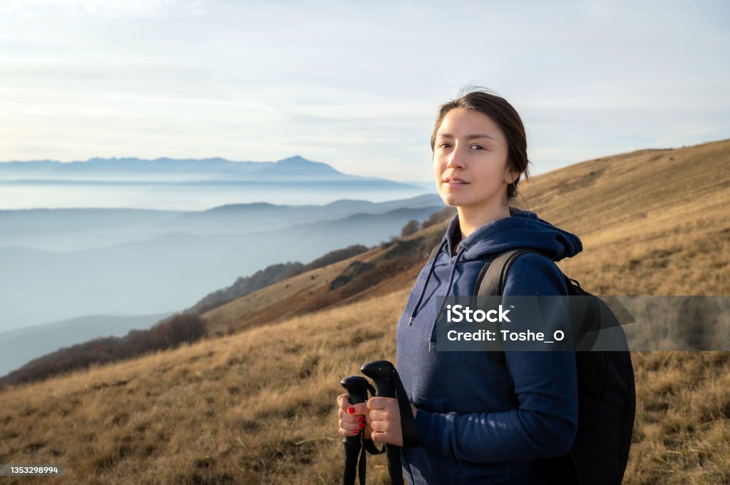 Woman conquers a mountain - moment of success Female superiority - shot of a young woman climbing a top of a mountain and celebrating the moment with wide spread arms Mountain Peak Stock Photo