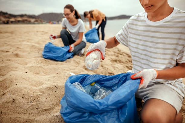 Volunteers cleaning the beach by collecting garbage into plastic bag