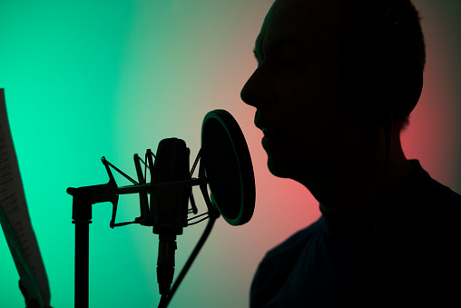 Actor de voz en off en estudio de grabación vocal con micrófono de diafragma larg y escudo antipop. photo