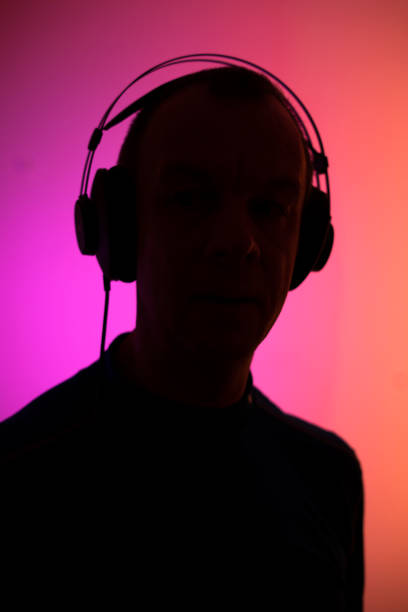 istock Dj deejay electronic wearing music headphones with coloured lights plain studio background. 1353302253