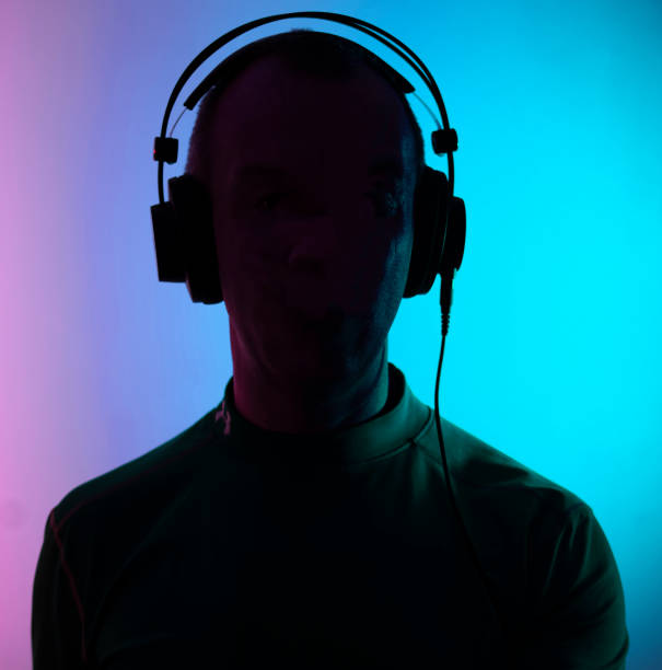 istock Dj deejay electronic wearing music headphones with coloured lights plain studio background. 1353302259