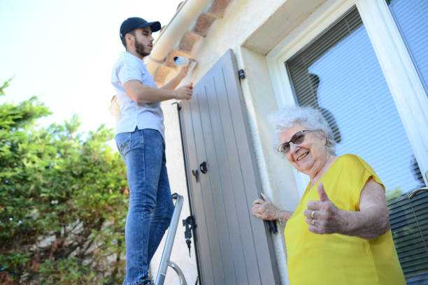 handsome young man installing house security anti burglary camera and siren alarm in senior woman home