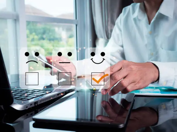 Photo of A man points with his finger and selects a face smiling emoticon to display on the virtual screen. A survey, poll, designed to gather information about user experience or customer satisfaction.