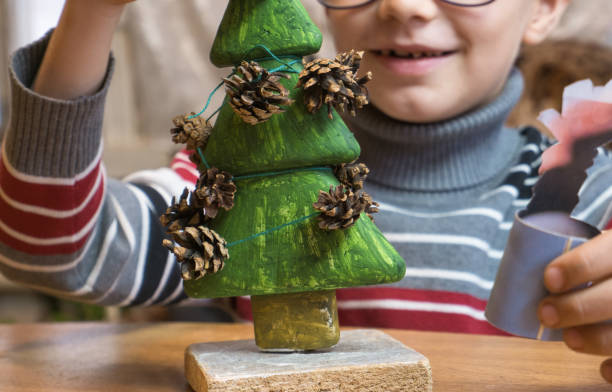 istock A little boy decorates a hand-made Christmas tree with pine cones and at the same time plays funny. 1353304870