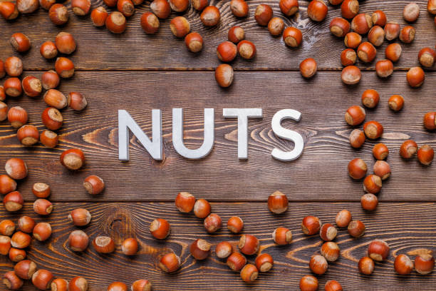 istock the word nuts laid with silver letters on wooden board background surrounded with scattered hazelnuts 1353318198