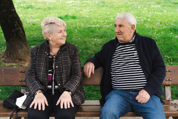 istock Elder couple laughing while sitting on park bench 1353319627