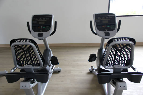 cyclette elettriche reclinabili in bianco e nero in una palestra per cardio, tonificazione gambe, bruciare calorie e perdere peso - spinning health club instructor gym foto e immagini stock