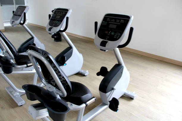 cyclette elettriche reclinabili in bianco e nero in una palestra per cardio, tonificazione gambe, bruciare calorie e perdere peso - spinning health club instructor gym foto e immagini stock