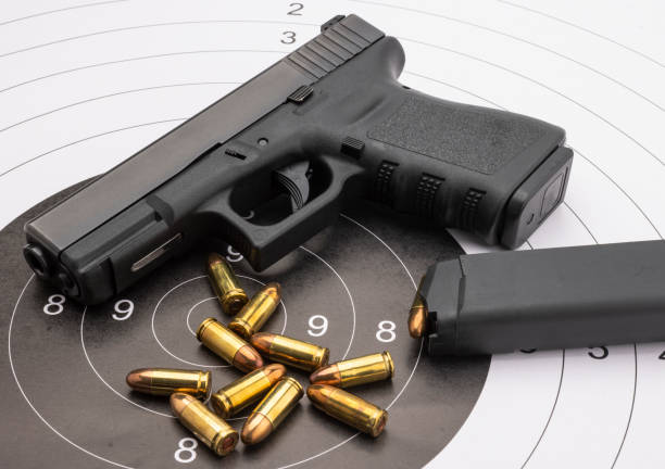 istock Semi automatic hand gun with bullets on paper target background , Shooting game 1353326686