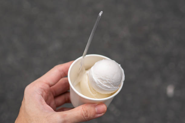 istock Coconut ice cream in a white paper cup in a hand 1353328602
