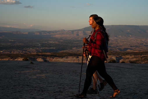 Young Couple Mixed Race Millennials Hiking Using Trekking Poles on a Giant Rock Formation at Dusk Near Fruita Colorado