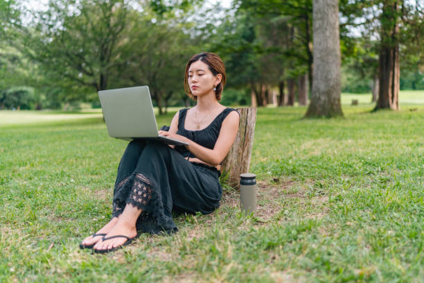 istock Young woman relaxing in nature and using laptop 1353329488