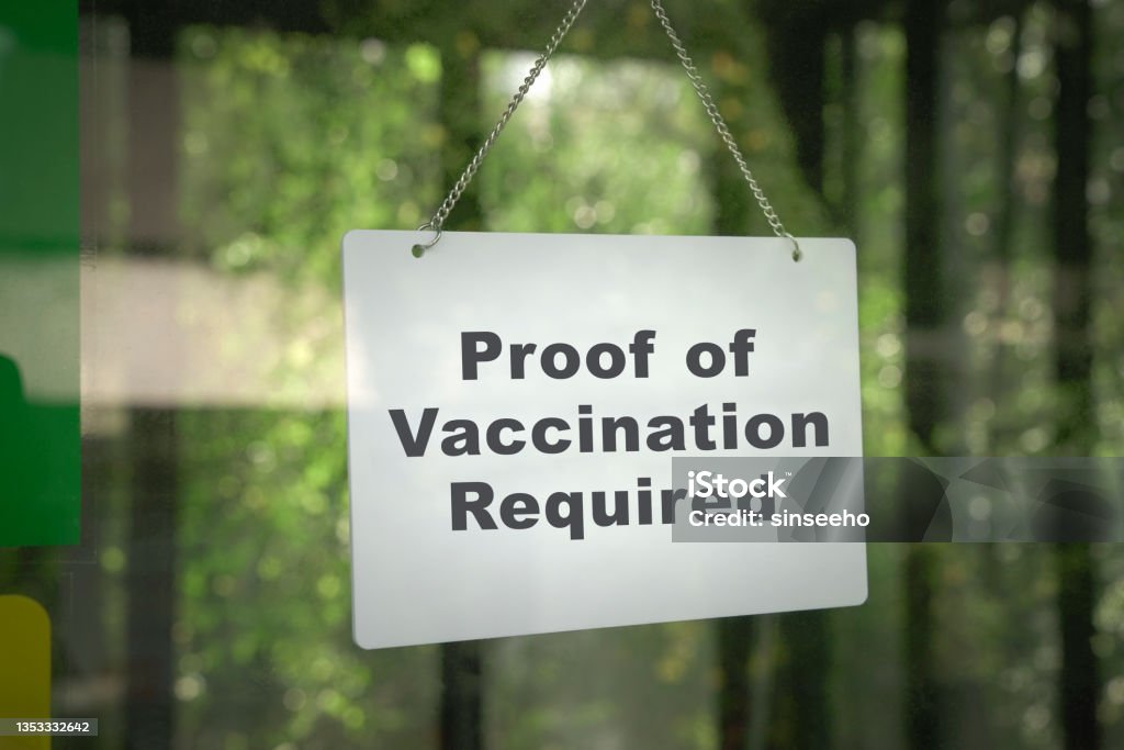 Signboard, Proof of Vaccination Required hanging on the door front of a shop. Signboard, Proof of Vaccination Required hanging on the door front of a shop. No vaccine, no entry concept. Vaccination Stock Photo