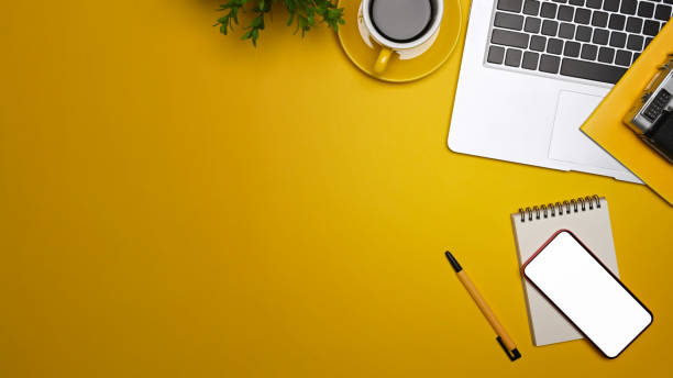 istock Overhead view laptop computer, smart phone and coffee cup on yellow background. 1353335458