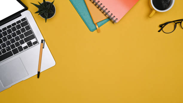 istock Mock up computer laptop, notebook and coffee cup on yellow background. 1353335495