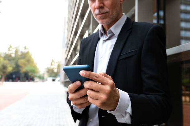 istock Unrecognizable caucasian man using mobile phone outside the office. Copy space. Selective focus on hands 1353336283